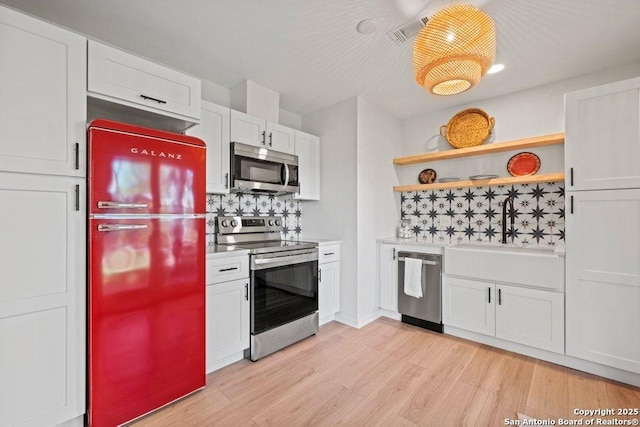 kitchen with white cabinets, open shelves, light countertops, stainless steel appliances, and light wood-style flooring