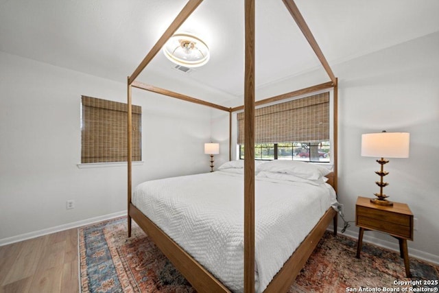 bedroom with visible vents, baseboards, and wood finished floors