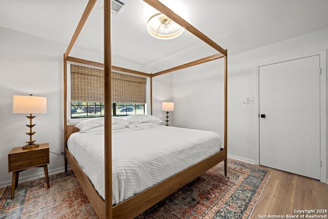 bedroom featuring visible vents, baseboards, and wood finished floors