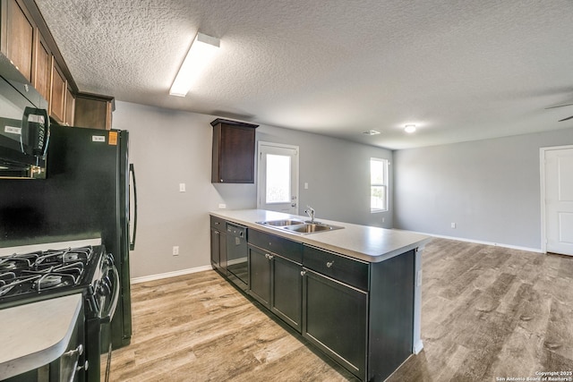 kitchen featuring a sink, light wood-style flooring, black appliances, and a peninsula