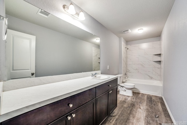 full bath with vanity, a textured ceiling, toilet, visible vents, and wood finished floors