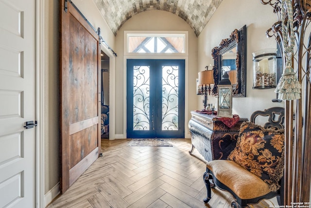 foyer entrance featuring a barn door, french doors, baseboards, and lofted ceiling