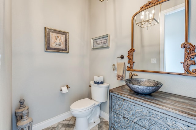 bathroom featuring toilet, baseboards, vanity, and a chandelier