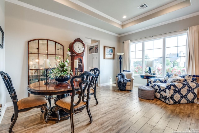 dining room with visible vents, baseboards, crown molding, a tray ceiling, and wood finished floors