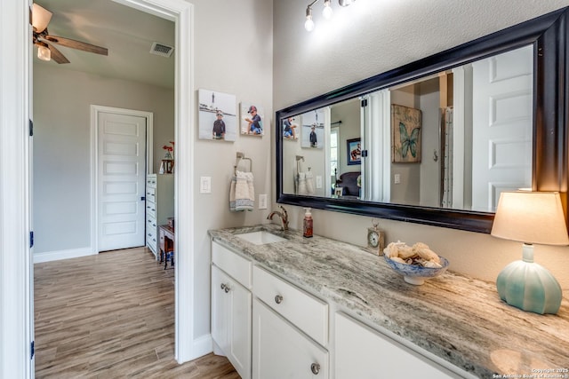 bathroom featuring vanity, a ceiling fan, visible vents, wood finished floors, and baseboards