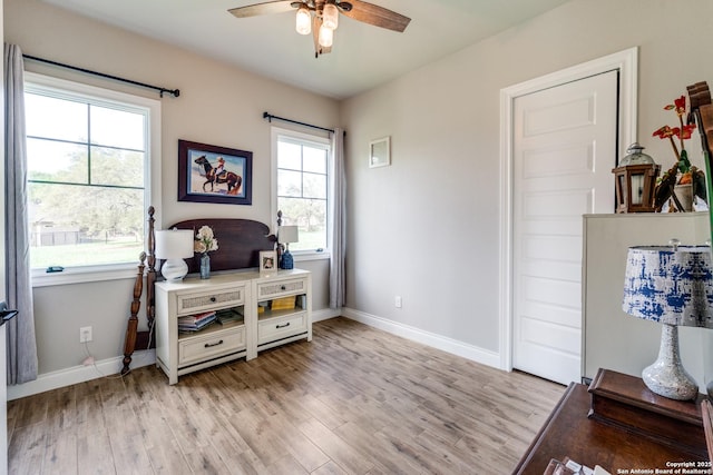 interior space with light wood-style flooring, a ceiling fan, and baseboards