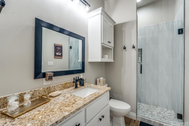 full bath featuring toilet, a shower stall, and vanity