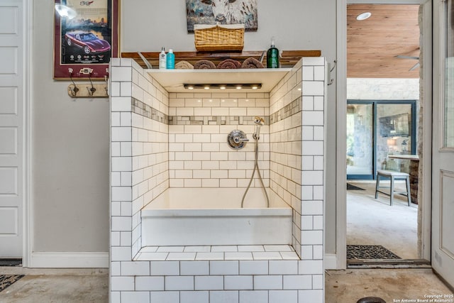 full bathroom with a tile shower and baseboards