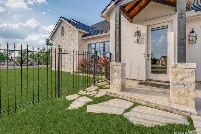 property entrance with fence, a gate, a lawn, and stucco siding