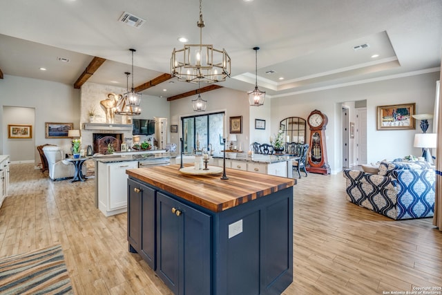 kitchen with butcher block countertops, a large island, open floor plan, light wood-style floors, and visible vents