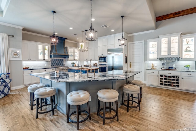 kitchen featuring visible vents, a large island, built in appliances, premium range hood, and decorative backsplash