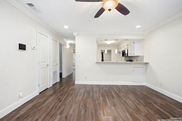 unfurnished living room with baseboards, ornamental molding, dark wood-type flooring, visible vents, and ceiling fan