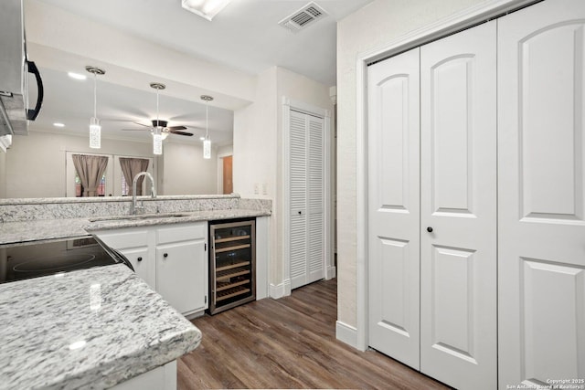 kitchen with dark wood-type flooring, visible vents, ceiling fan, beverage cooler, and a sink