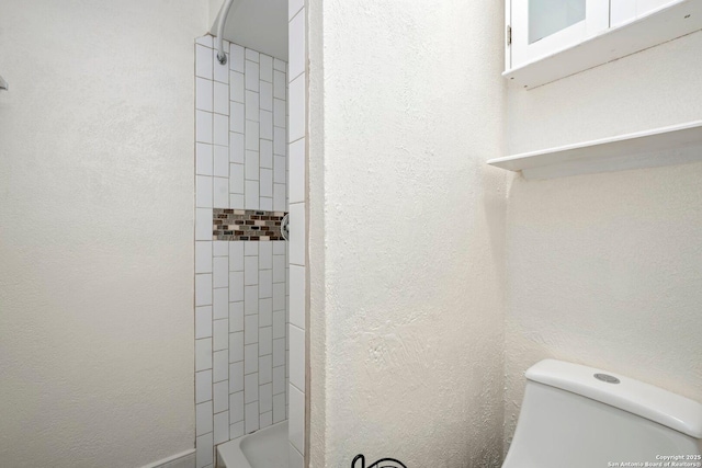 full bathroom featuring toilet, a shower, and a textured wall