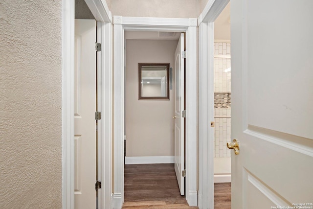 corridor featuring baseboards and wood finished floors