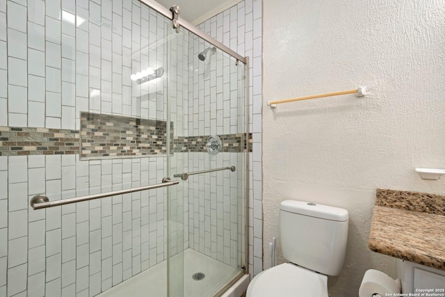 bathroom with a shower stall, toilet, and a textured wall