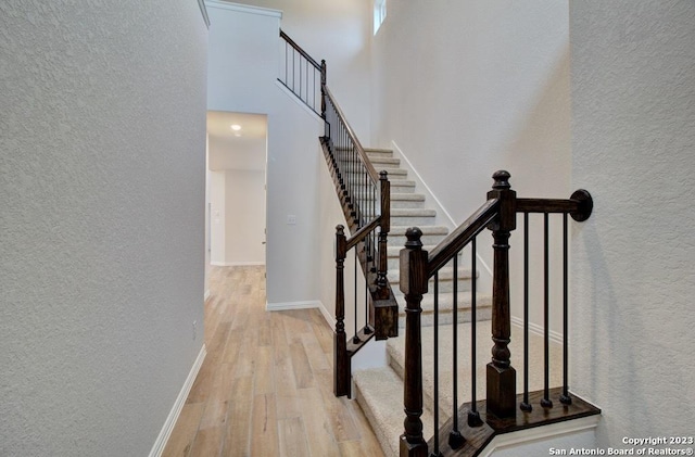 883 Casetta Trl, New Braunfels, TX 78130 - staircase featuring wood finished floors, a textured wall, a towering ceiling, and baseboards