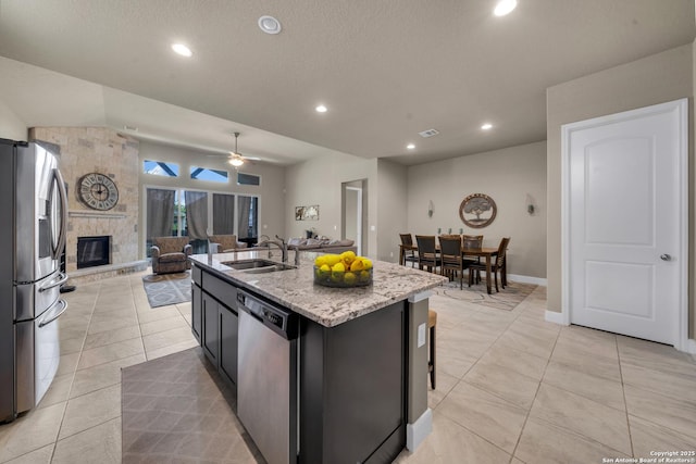11347 Phoebe Lace, San Antonio, TX 78253 - kitchen featuring a sink, open floor plan, a stone fireplace, appliances with stainless steel finishes, and light stone countertops