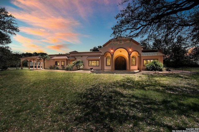 mediterranean / spanish house with a garage, stucco siding, and a lawn