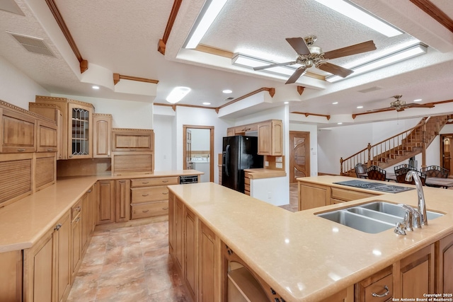 kitchen featuring ceiling fan, a large island with sink, visible vents, black fridge, and a sink