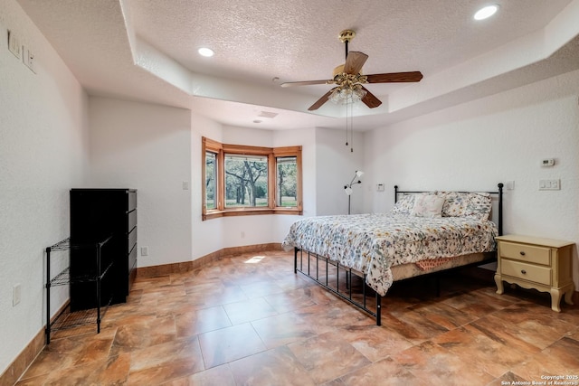 bedroom featuring baseboards, recessed lighting, a textured ceiling, a ceiling fan, and a raised ceiling