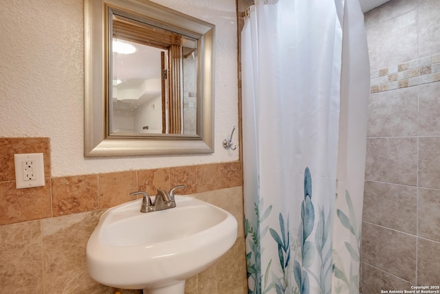 bathroom with curtained shower, a textured wall, and a sink