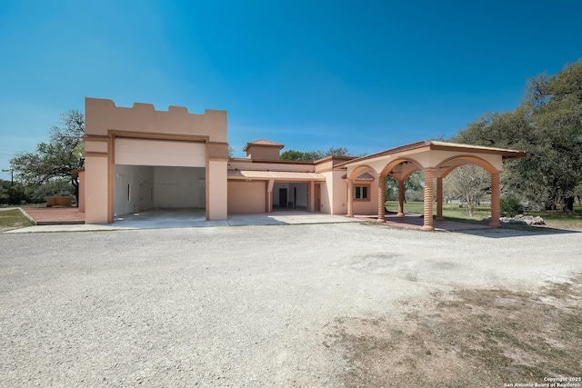 view of front of house featuring gravel driveway, a garage, and stucco siding