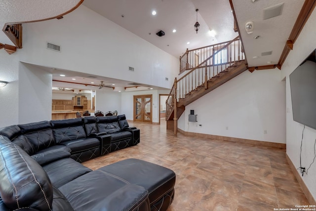 living room with visible vents, baseboards, a high ceiling, and stairs