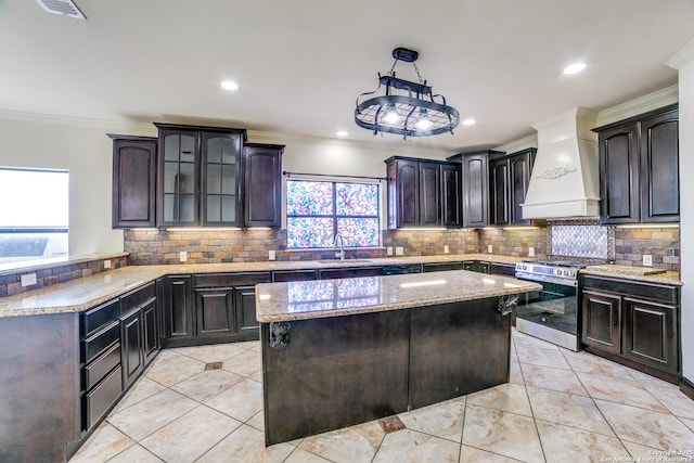 12022 Del Rio Run, San Antonio, TX 78245 - kitchen with custom exhaust hood, tasteful backsplash, ornamental molding, stainless steel range with gas stovetop, and a sink
