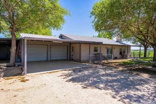 single story home featuring a garage, brick siding, a chimney, and dirt driveway
