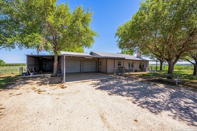 view of front facade with metal roof, a garage, a chimney, fence, and driveway
