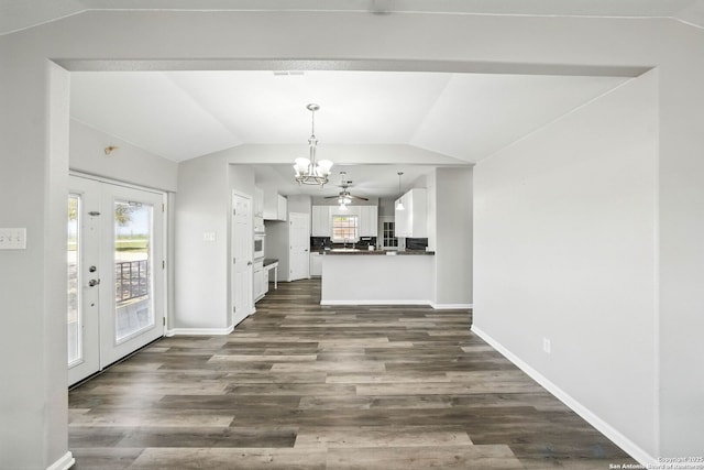unfurnished living room with dark wood-style floors, a notable chandelier, baseboards, and lofted ceiling