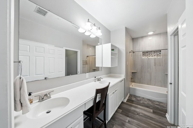 bathroom with wood finished floors, double vanity, a sink, and visible vents