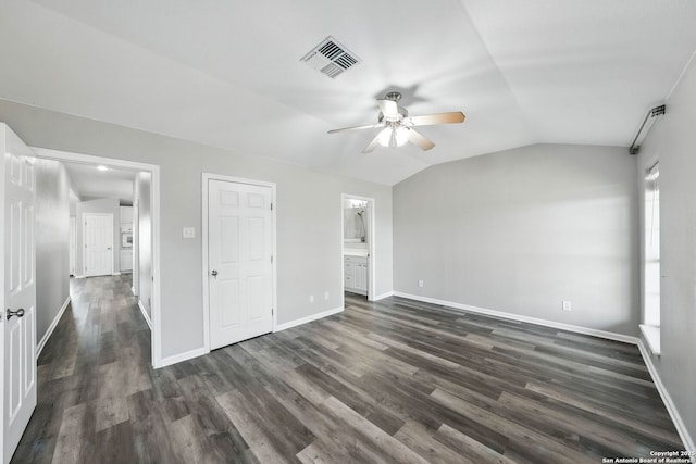 unfurnished bedroom featuring visible vents, baseboards, ensuite bath, vaulted ceiling, and dark wood-type flooring
