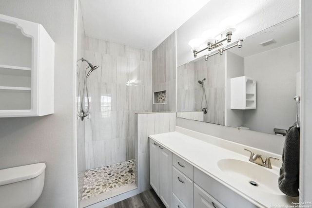 full bathroom with vanity, walk in shower, toilet, visible vents, and wood finished floors