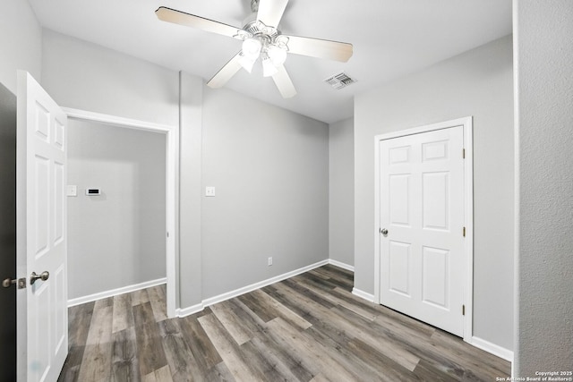 unfurnished bedroom featuring visible vents, baseboards, ceiling fan, and wood finished floors