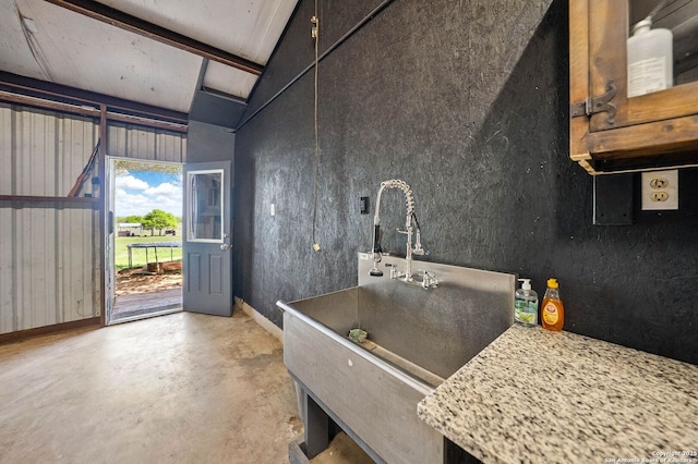 kitchen with beamed ceiling, baseboards, and concrete flooring