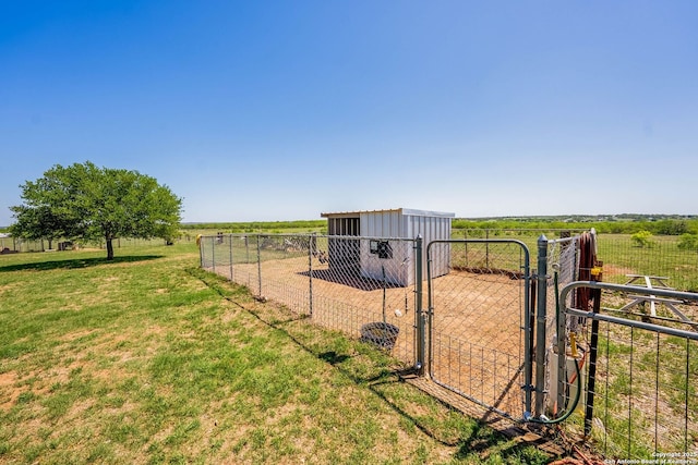 view of yard with an outdoor structure, fence, a gate, and a rural view