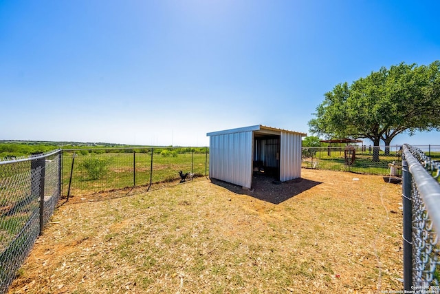 view of yard with a rural view, fence, and an outbuilding