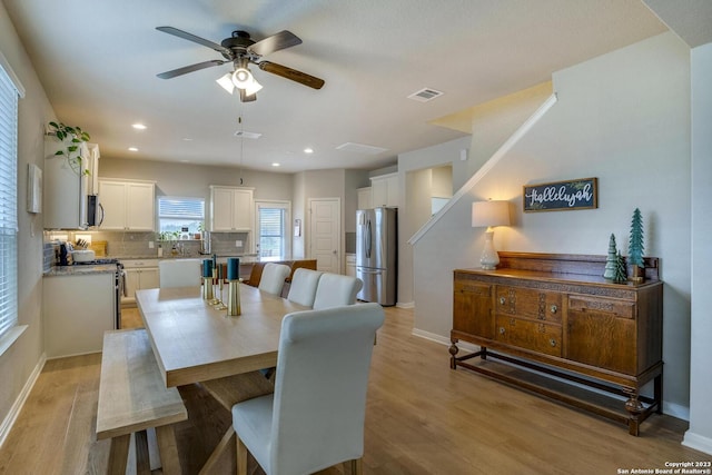 dining room featuring light wood finished floors, visible vents, baseboards, and a ceiling fan