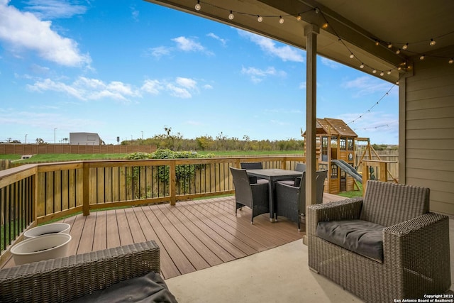 deck with a playground and outdoor dining area