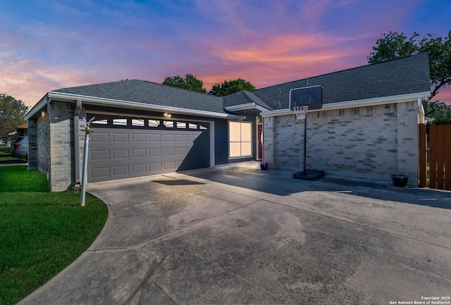 single story home with a front yard, a shingled roof, a garage, brick siding, and driveway