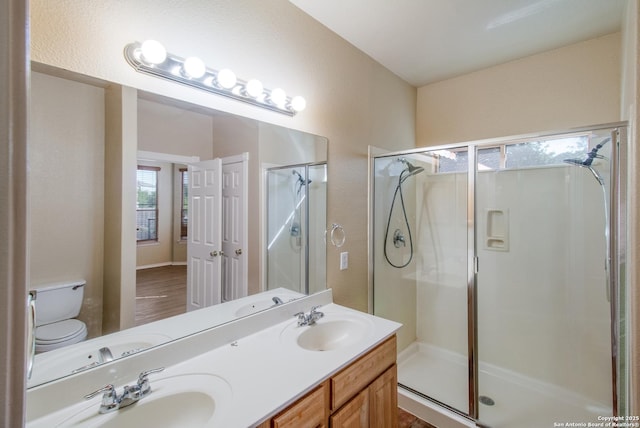 full bathroom with toilet, a stall shower, double vanity, and a sink