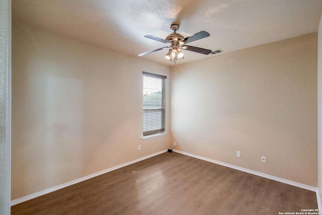 empty room featuring wood finished floors, ceiling fan, baseboards, and visible vents