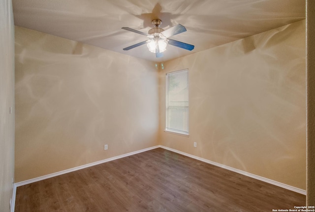 empty room featuring a ceiling fan, baseboards, and dark wood-style floors