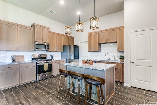 kitchen with wood finish floors, visible vents, a breakfast bar, a center island, and stainless steel appliances