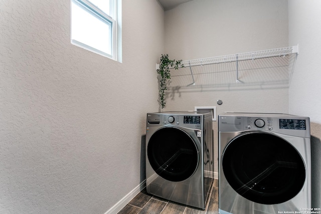 clothes washing area featuring separate washer and dryer, baseboards, wood finish floors, a textured wall, and laundry area