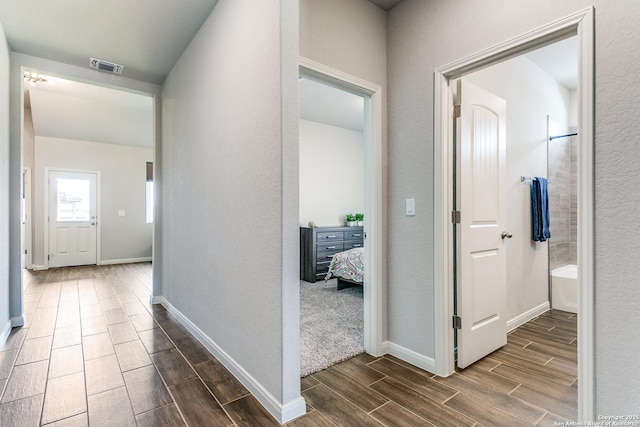 hall featuring wood finish floors, baseboards, and visible vents