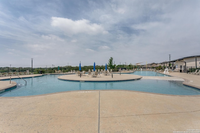 community pool with a patio and fence