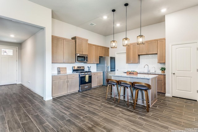 kitchen with a kitchen island, wood tiled floor, a breakfast bar area, stainless steel appliances, and pendant lighting